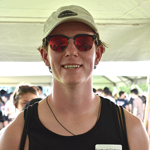 young man wearing sunglasses standing inside tent