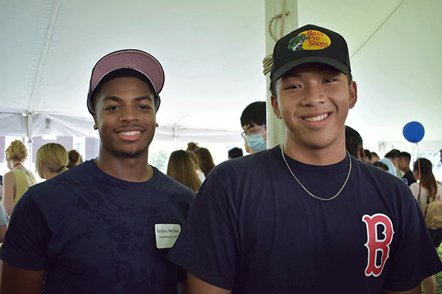 two young men in ball caps standing next to each other in tent