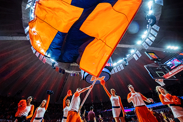 cheerleaders at University of Illinois basketball game, waving large blue and orange"I" flag