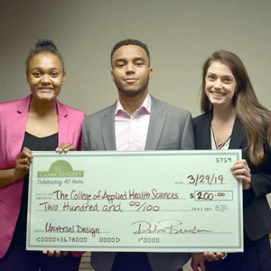 3 students holding a giant check for $200