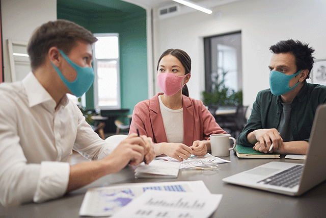 students sitting around a table wearing antiviral masks