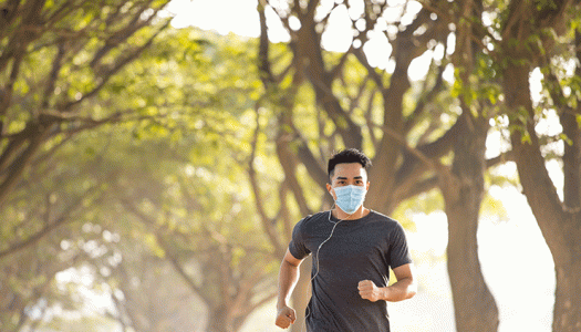 young man running outside wearing safety mask
