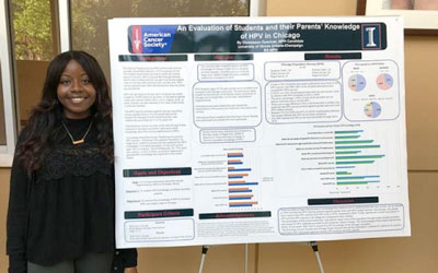 student standing in front of large informational poster